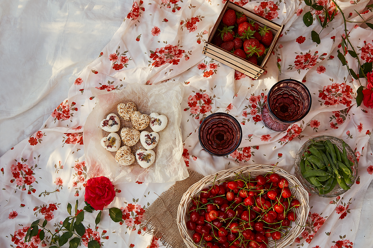 summer picnic on floral cloth with cherries cookies and two glasses
